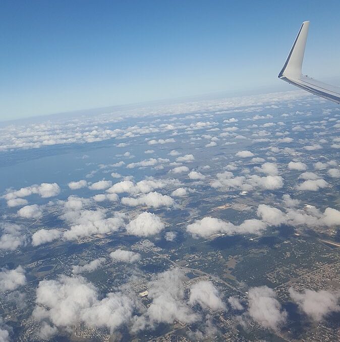 The sky and land below, when see from an airplane window. The tip of the wing is also in view.